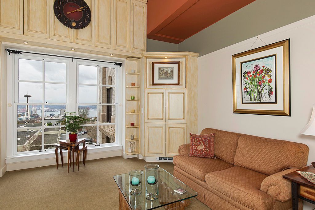 A living room with a large multi paned window showing a Space Needle view. A orange-brown couch is to the right.