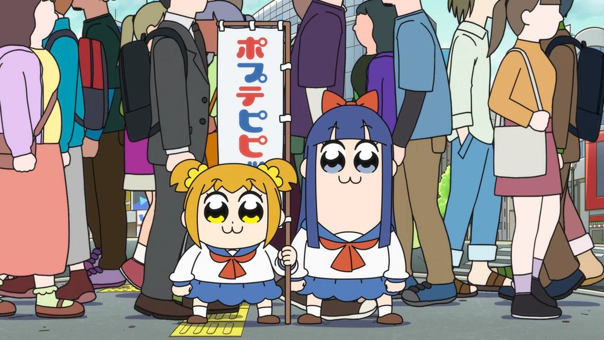 two anime girls, one yellow haired and the other blue haired, stand in the middle of a bustling crosswalk intersection with a cloth banner behind them with the words, “Pop Team Epic,” written in Japanese.