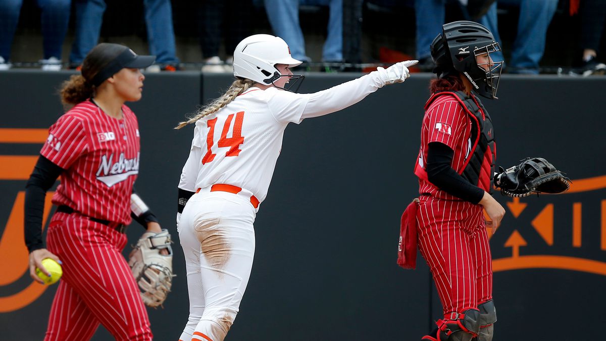 Oklahoma State’s Karli Petty (14) celebrates a score in the second inning in between Nebraska’s Courtney Wallace (23) and Anni Raley (33) during the Stillwater Regional in 2022 NCAA softball tournament game between Oklahoma State Cowgirls and Nebraska Cornhuskers at Cowgirl Stadium in Stillwater, Okla.