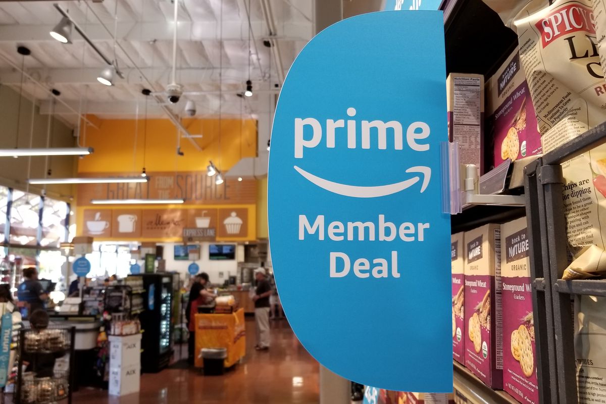 Signage at a Whole Foods Market grocery store, on a shelf of chips, advertising new discounts for members of the Amazon Prime service from Amazon.