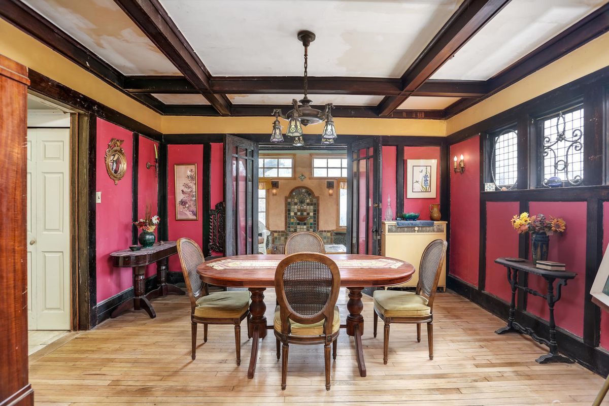 Red-painted panels are separated by dark wood molding. There’s an oval wood table surrounded by four chairs.