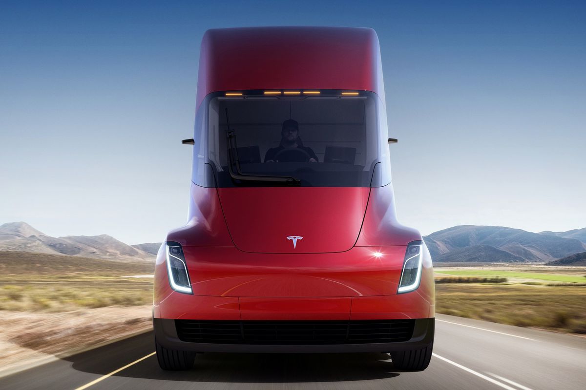 The front end of a Tesla semi driving down a deserted road toward the camera.
