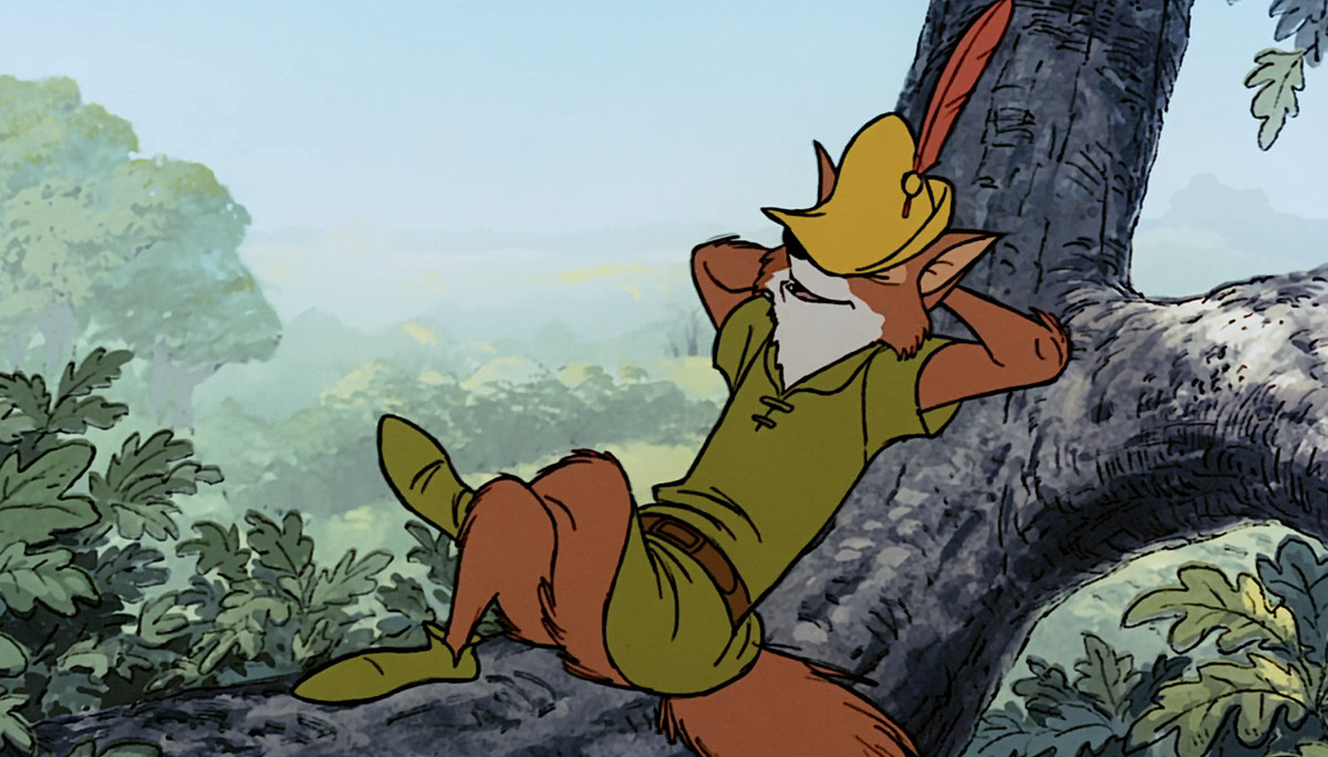 Disney’s Robin Hood, an anthropomorphic fox in green, lounges casually on his back on a tree branch with his peaked hat partially covering his face in the 1973 animated movie