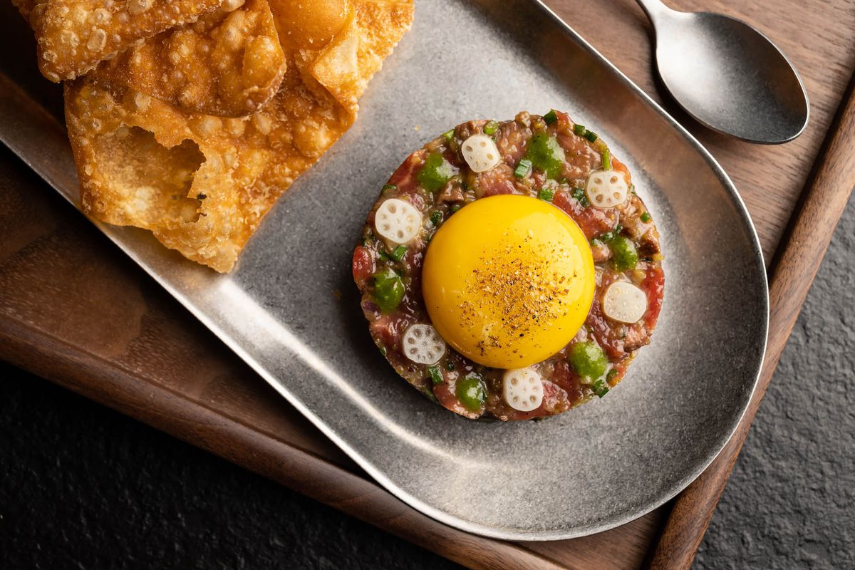 Raw beef with cured egg yolk and crispy sides for dipping at a restaurant.