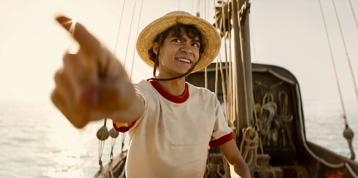 Iñaki Godoy as Monkey D. Luffy pointing his finger outward while atop the deck of a pirate ship in broad daylight in One Piece.