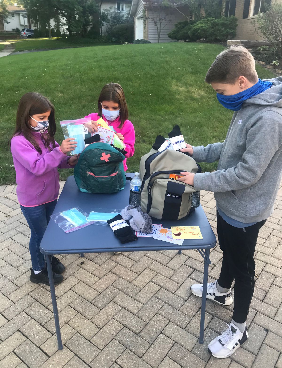 Ryan Gustis and volunteers Julia and Maria Krapec pack essentials such as socks and toiletries into backpacks to be distributed to homeless people.&nbsp;