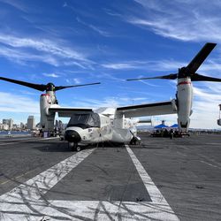 A V-22 Osprey sits amid-ship tied down to the flight deck of the USS Abraham Lincoln (CVN-72) on display for those in attendance to view.