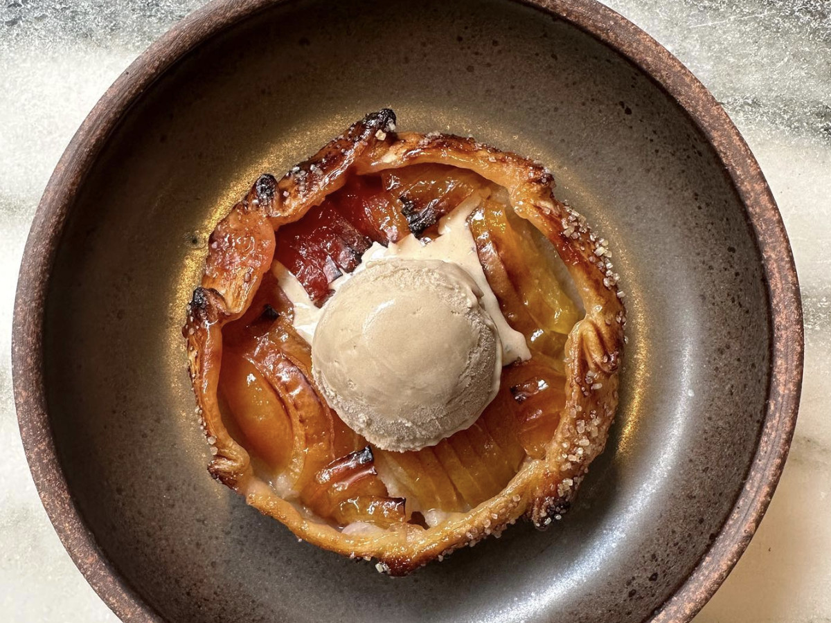 A plum galette topped with a scoop of ice cream in a round bowl.