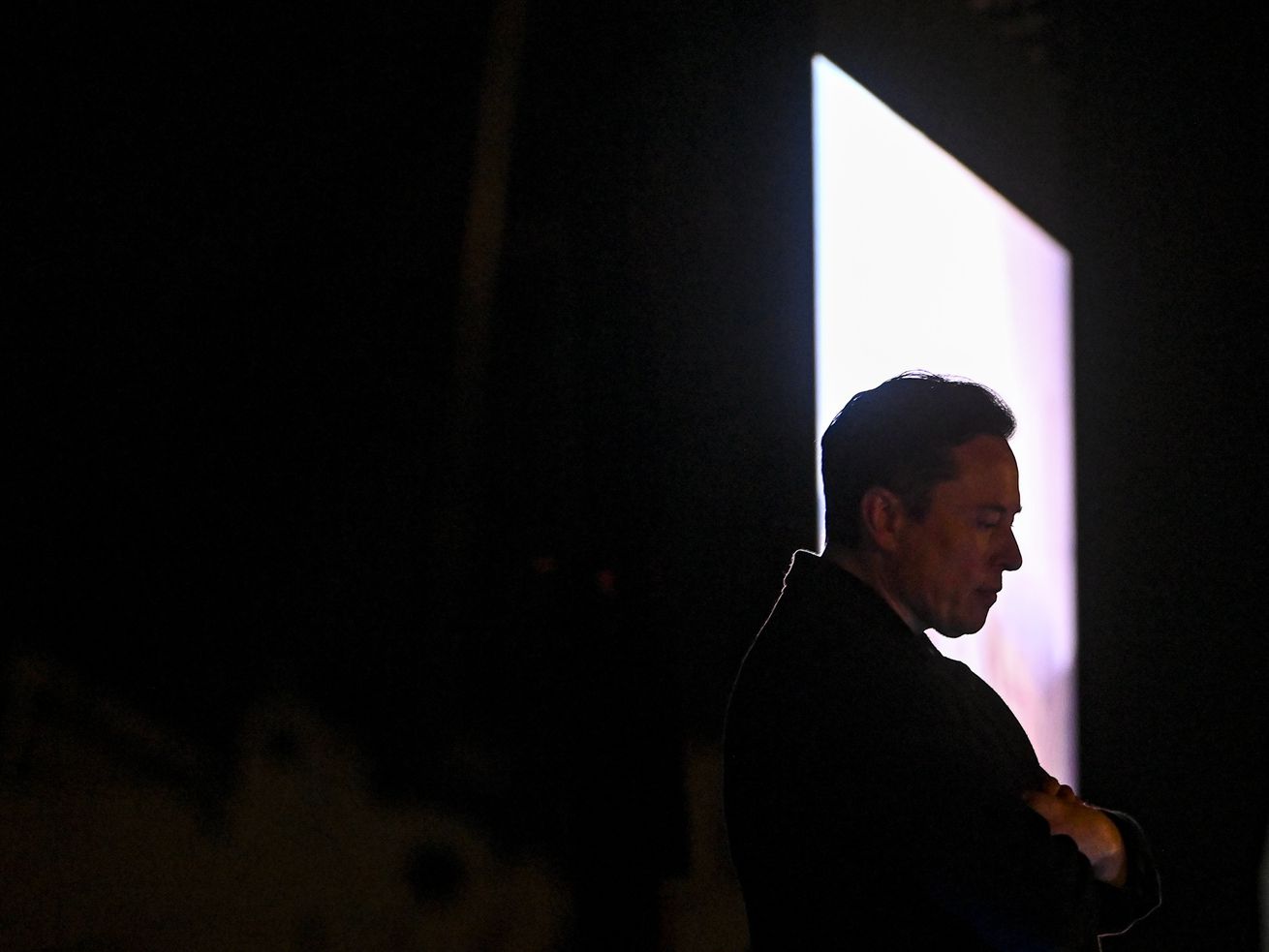 Elon Musk in profile, silhouetted in a rectangle of light.