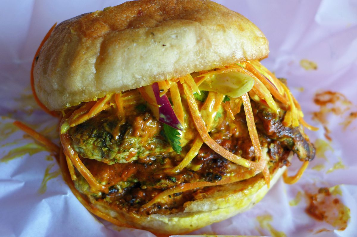 A grilled chicken sandwich with carrot slaw slices hanging over the patty like bangs.