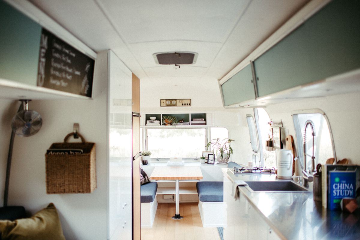 The interior of an Airstream travel trailer with eggshell blue cabinets, stainless steel countertops, and a dinette. 