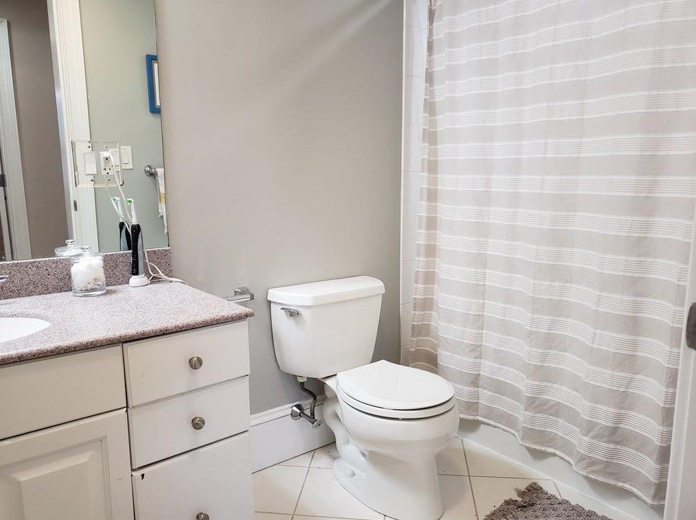 A bathroom with a vanity next to a toilet next to a shower with the curtain pulled closed. 