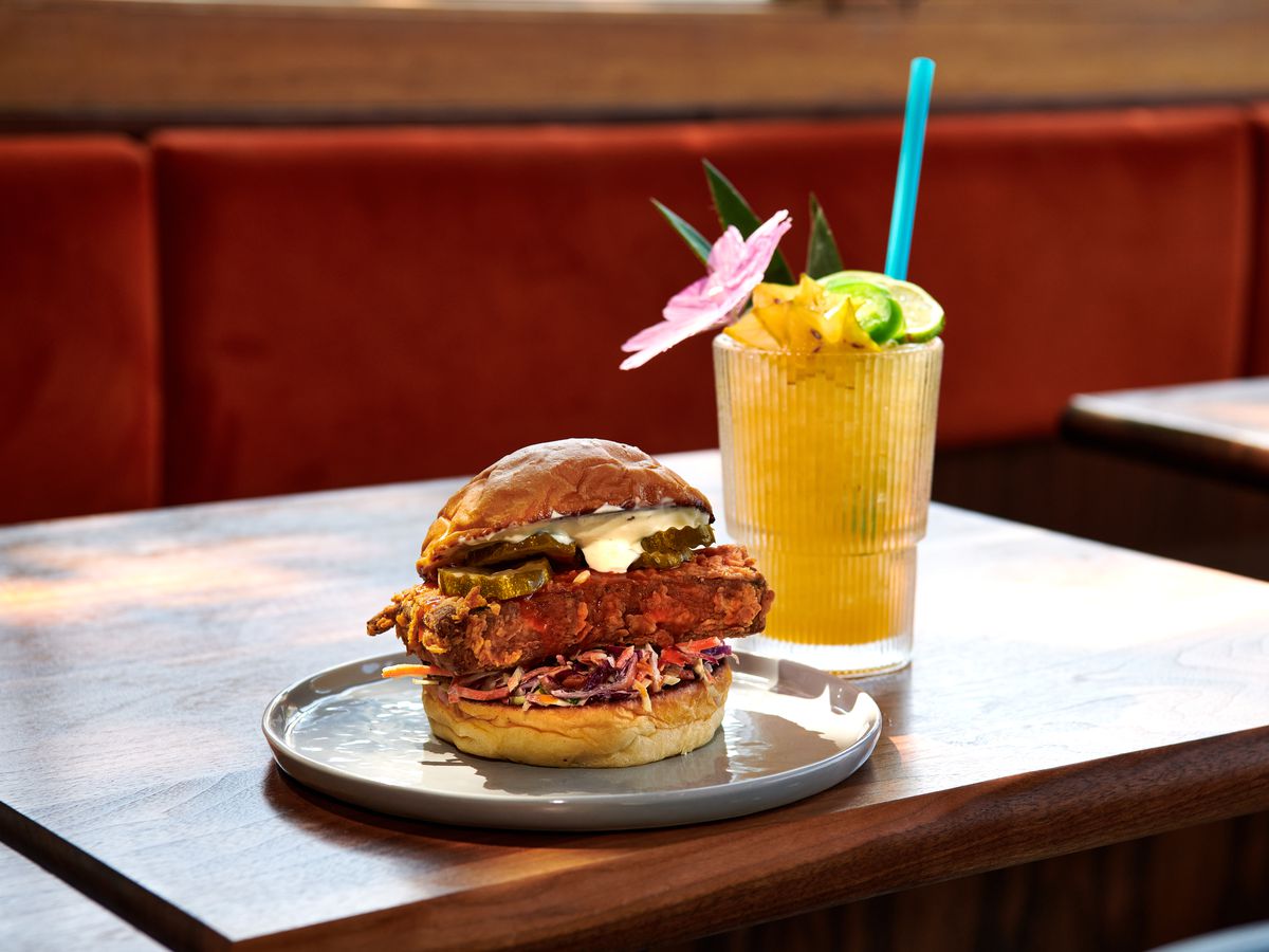 A fried tofu sandwich sits next to a cocktail garnished with starfruit at Jojo.
