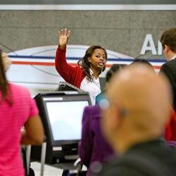 In this Tuesday, April 16, 2013, file photo, an American Airlines ticket agent talks assists passengers checking in at Hartsfield-Jackson airport, in Atlanta. AMR Corp. reports quarterly financial results before the market opens on Wednesday, April 17, 2013.