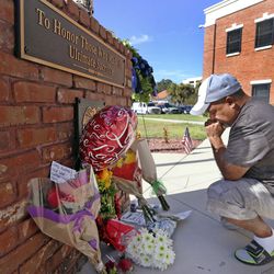 CORRECTS STATUS OF SECOND POLICE OFFICER - After placing flowers at a makeshift memorial, Miguel Velez, say's a prayer for the officer that was killed on Saturday, Aug. 19, 2017 in Kissimmee, Fla. The Kissimmee Police Department says Sgt. Sam Howard died Saturday from his injuries. His colleague, Officer Matthew Baxter, died Friday night after the attack in a neighborhood of Kissimmee, located south of the theme park hub of Orlando.