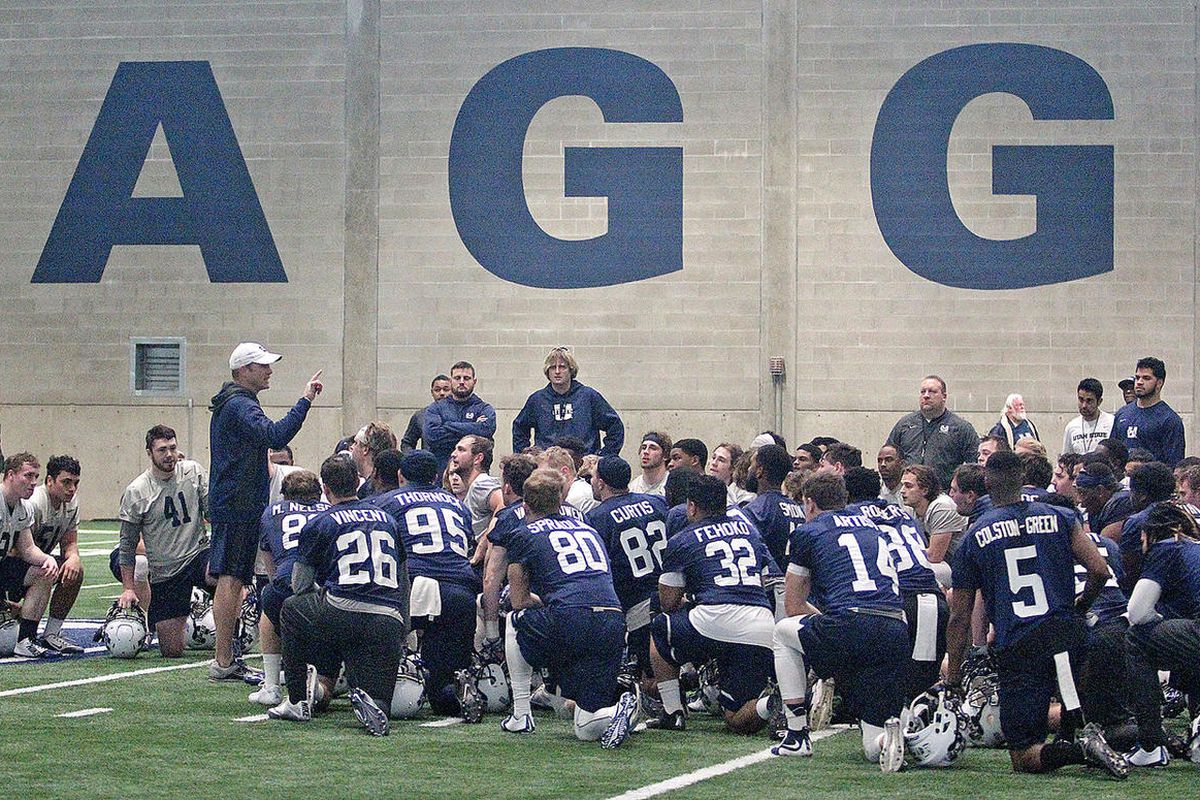 USU head coach Matt Wells, left, addresses his team following the Aggies' first practice of spring football Tuesday morning at the Stan Laub Indoor Training Center in Logan. 