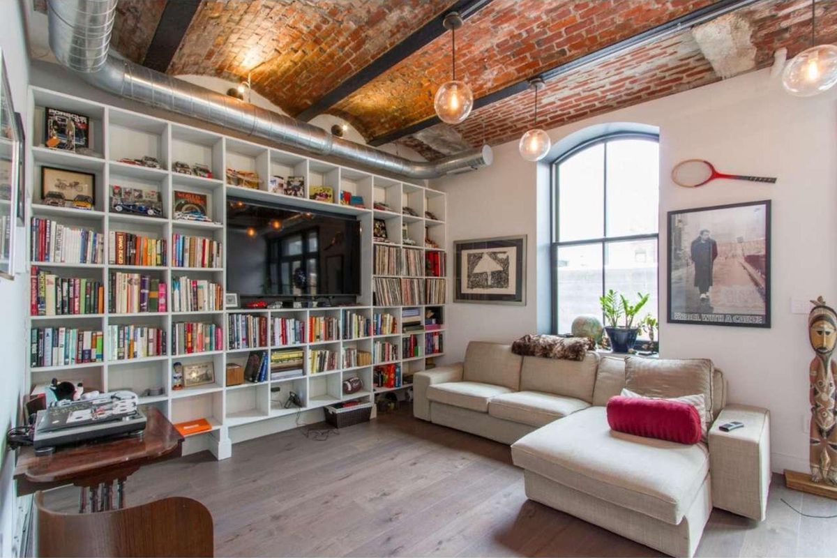 A living room with a wall of built-in bookcases and brick barrel ceilings. 