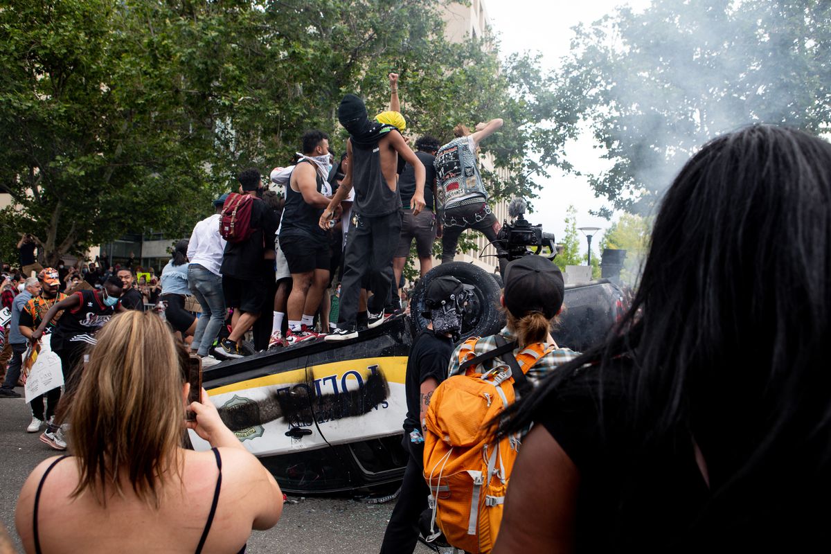People jump on top of an overturned police car as they protest police brutality in Salt Lake City on Saturday, May 30, 2020. Protesters joined others across the nation after George Floyd, a Black man in Minnesota, died at the hands of police on Memorial Day.