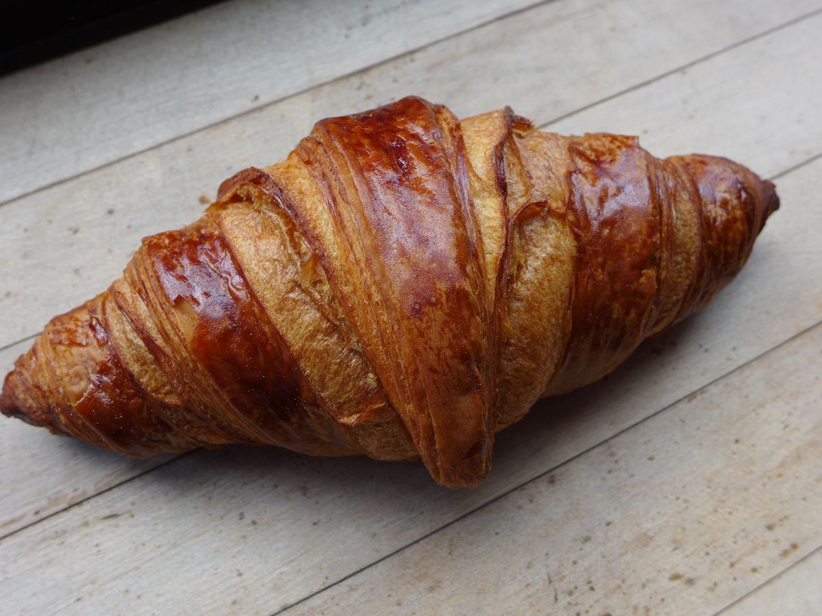 A croissant tilted diagonally on a wooden surface.
