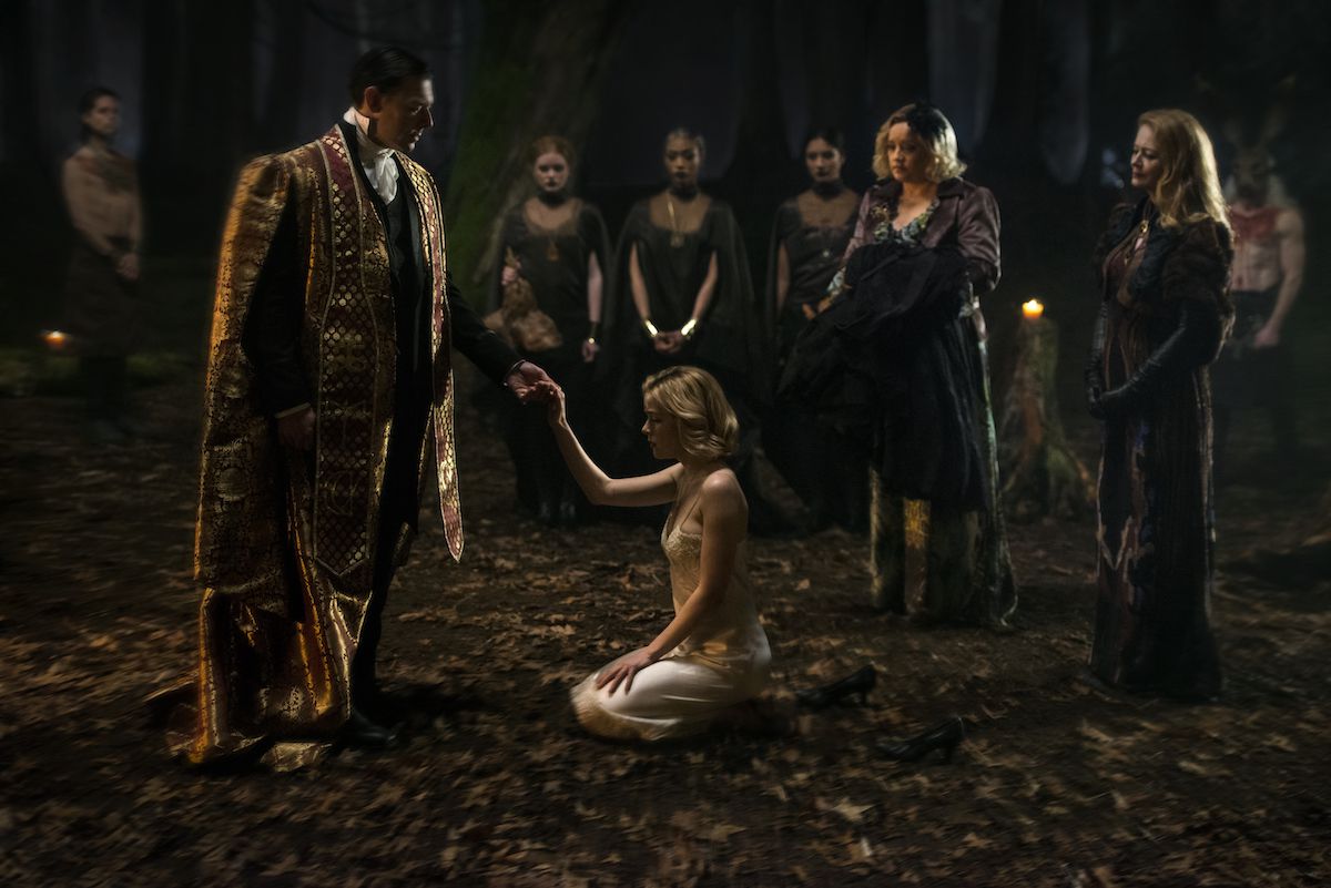 Chilling Adventures of Sabrina - Sabrina kneeling in a circle of people in the forest