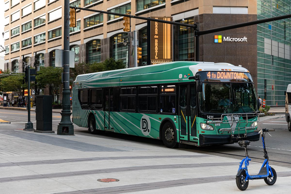 A green and white bus in front of a large office building.