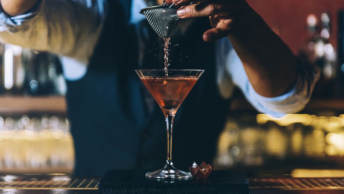 A bartender pouring a cocktail.