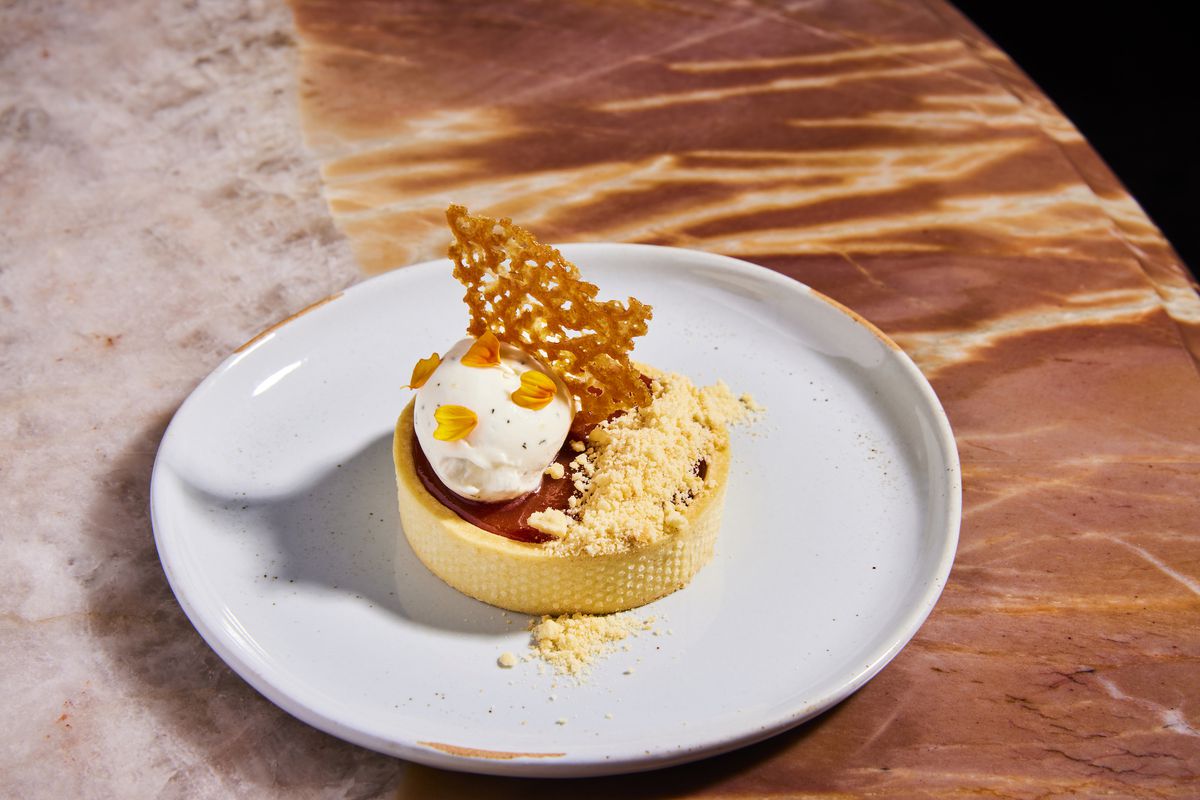 A round pastry dessert, yellow, with a creamy dollop on top at new LA restaurant Que Barbaro.