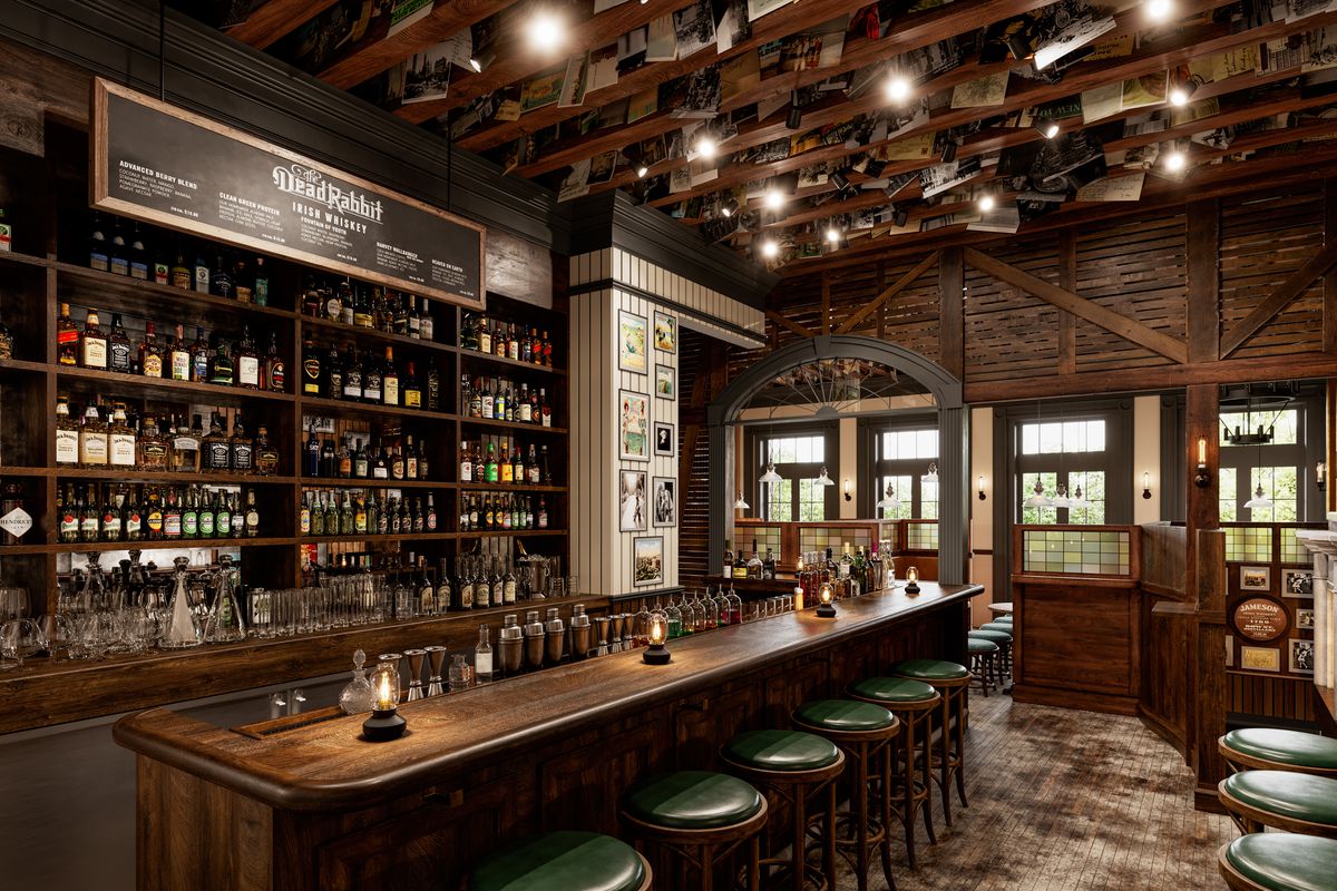 A dark wooden bar with high ceilings and many liquor bottles stacked on the back wall.