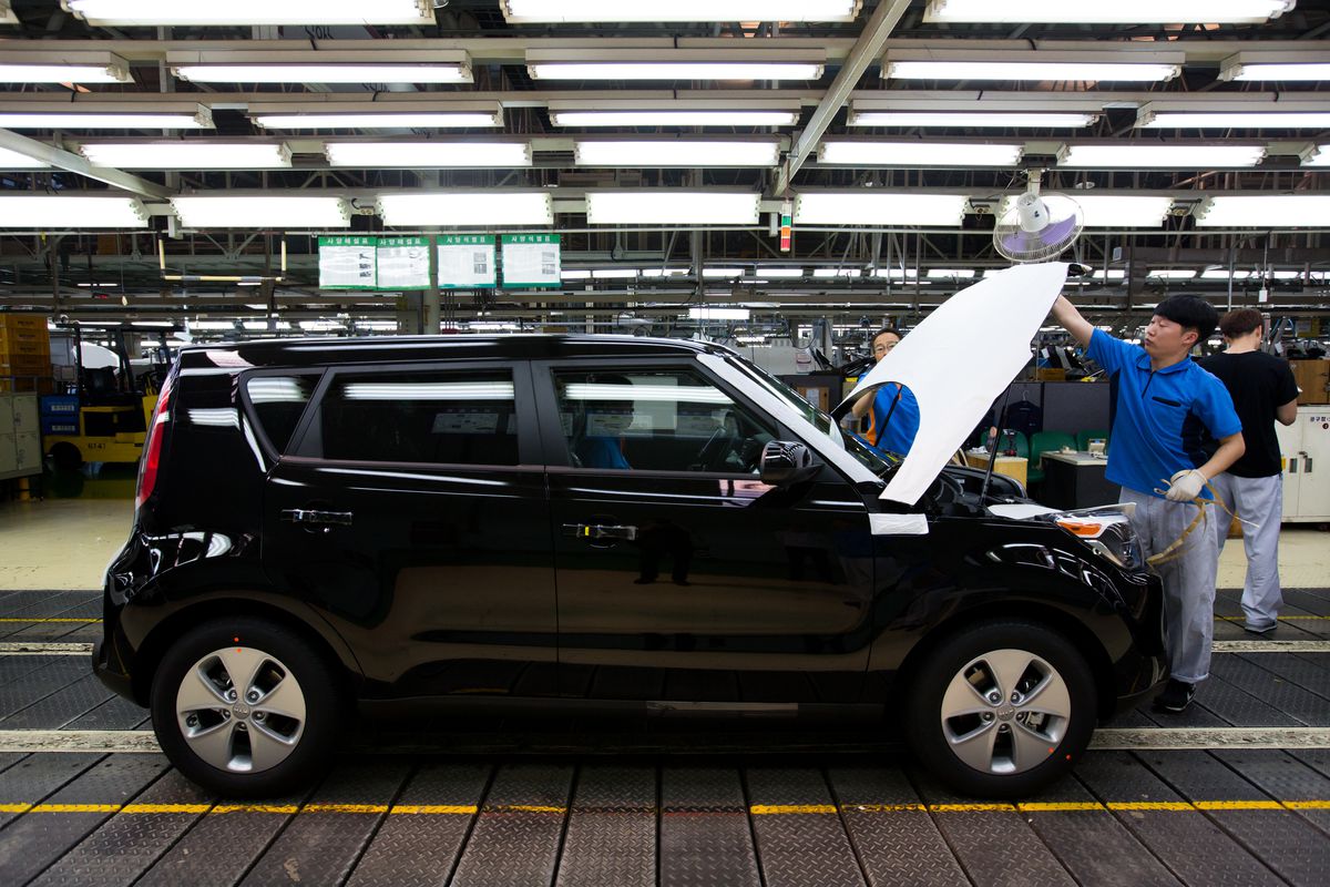 A factory worker inspects a Kia Soul in a factory.