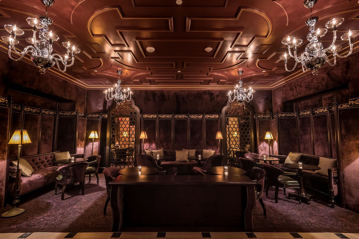 Velvet couches, dark furniture, and chandeliers in a lobby.