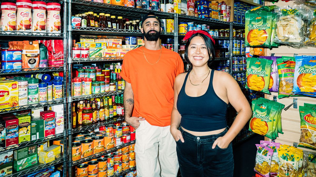 Luis Fernandez and Isabel Lee stand in front of the bodega shelves at Don Juan Deli.