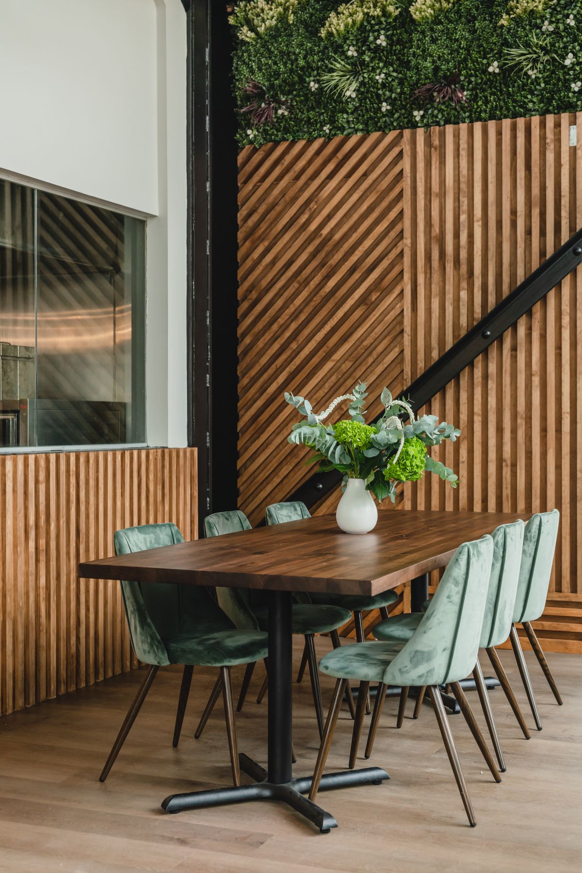 A dining table with light green chairs in front of a wood-paneled wall.
