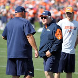 Broncos Defensive Coordinator Wade Phillips (M) talks with his coaches before drills begin