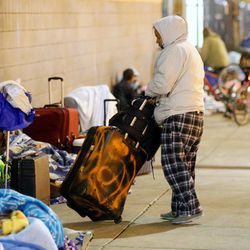 A woman moves a rolling suitcase as she and other homeless folks sit outside the winter overflow shelter at St. Vincent de Paul in Salt Lake City on Wednesday, Nov. 16, 2016.