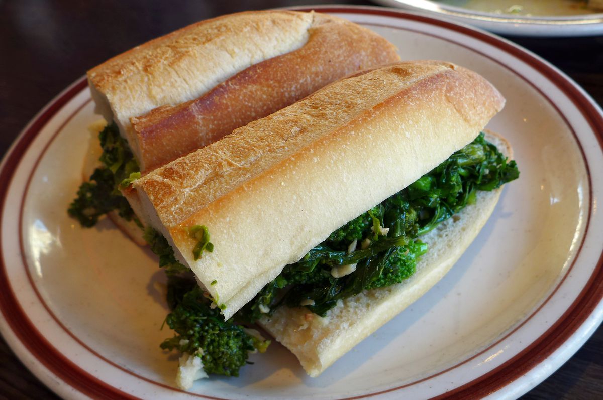 A hero sandwich with green vegetable inside.