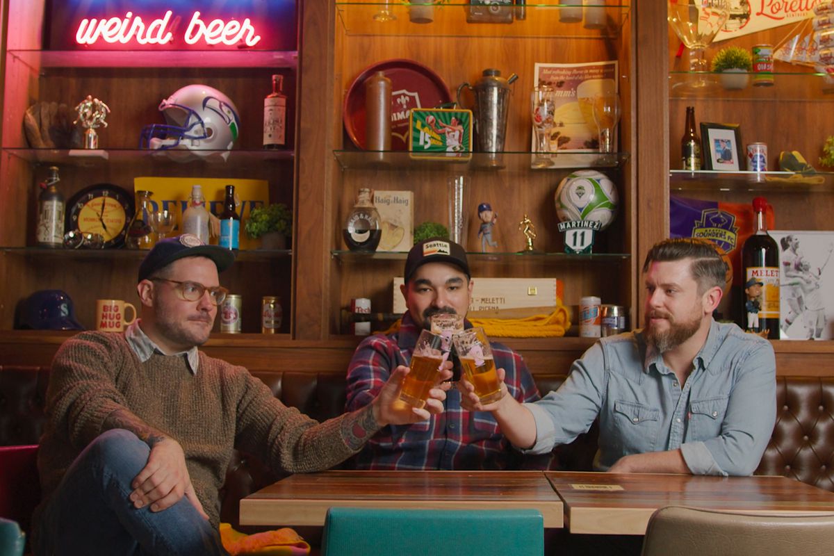 Three bearded men cheers pints of beer.