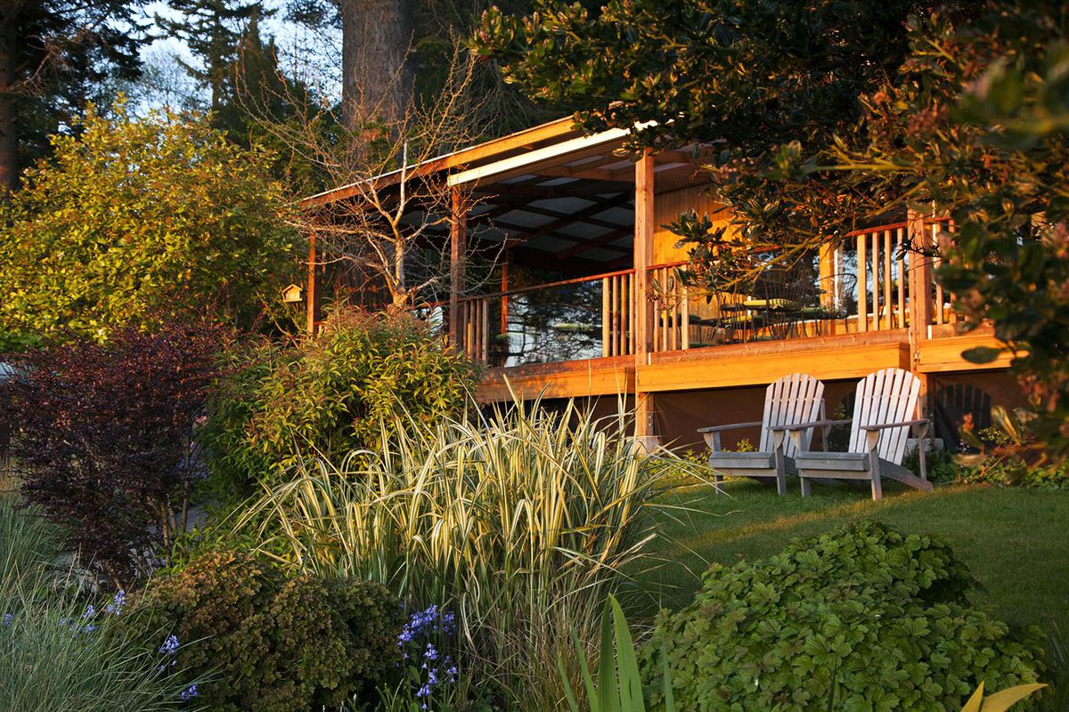 A view of Willows Inn on Lummi Island, with two deck chairs out front and foliage all around