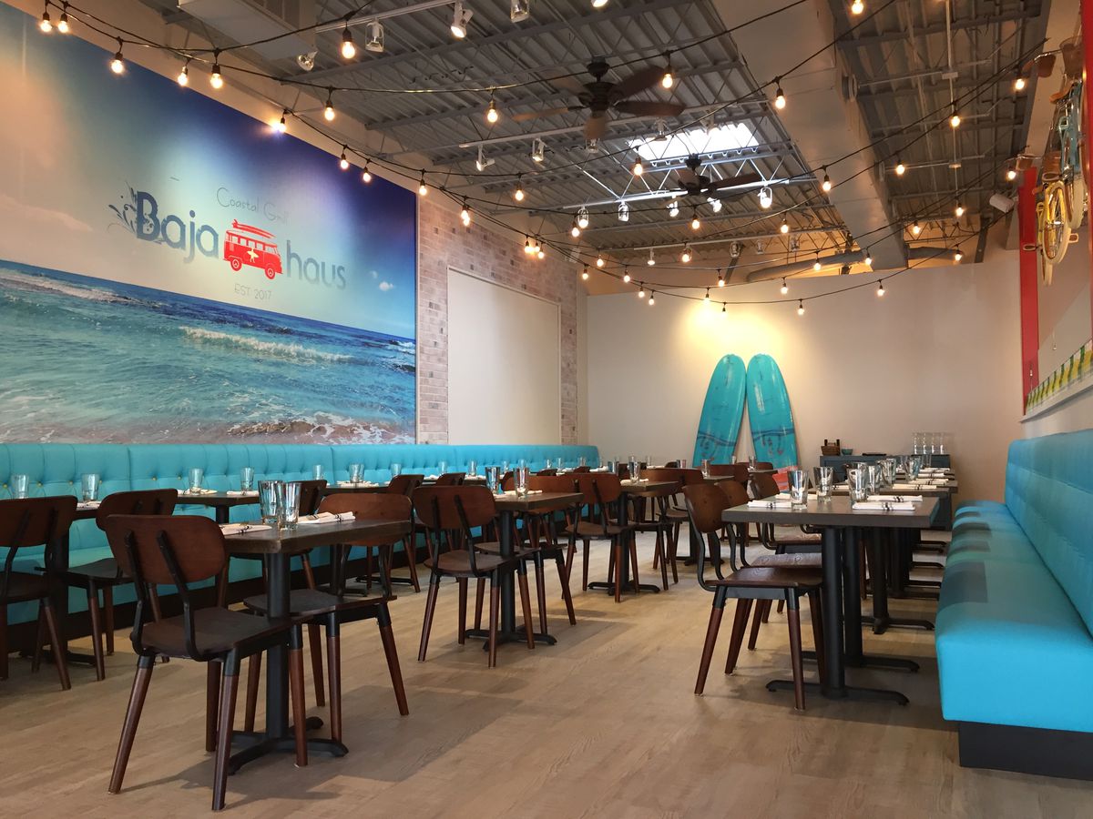 A dining room with an ocean mural, two surfboards in the back and a ceiling with strings of lights