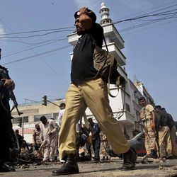 Pakistani police officers gather at the site of a bomb blast in Karachi, Pakistan, Wednesday, June 26, 2013. A bomb targeting a senior judge in the southern Pakistani city of Karachi wounded him and killed several security personnel on Wednesday, a senior government official said. 