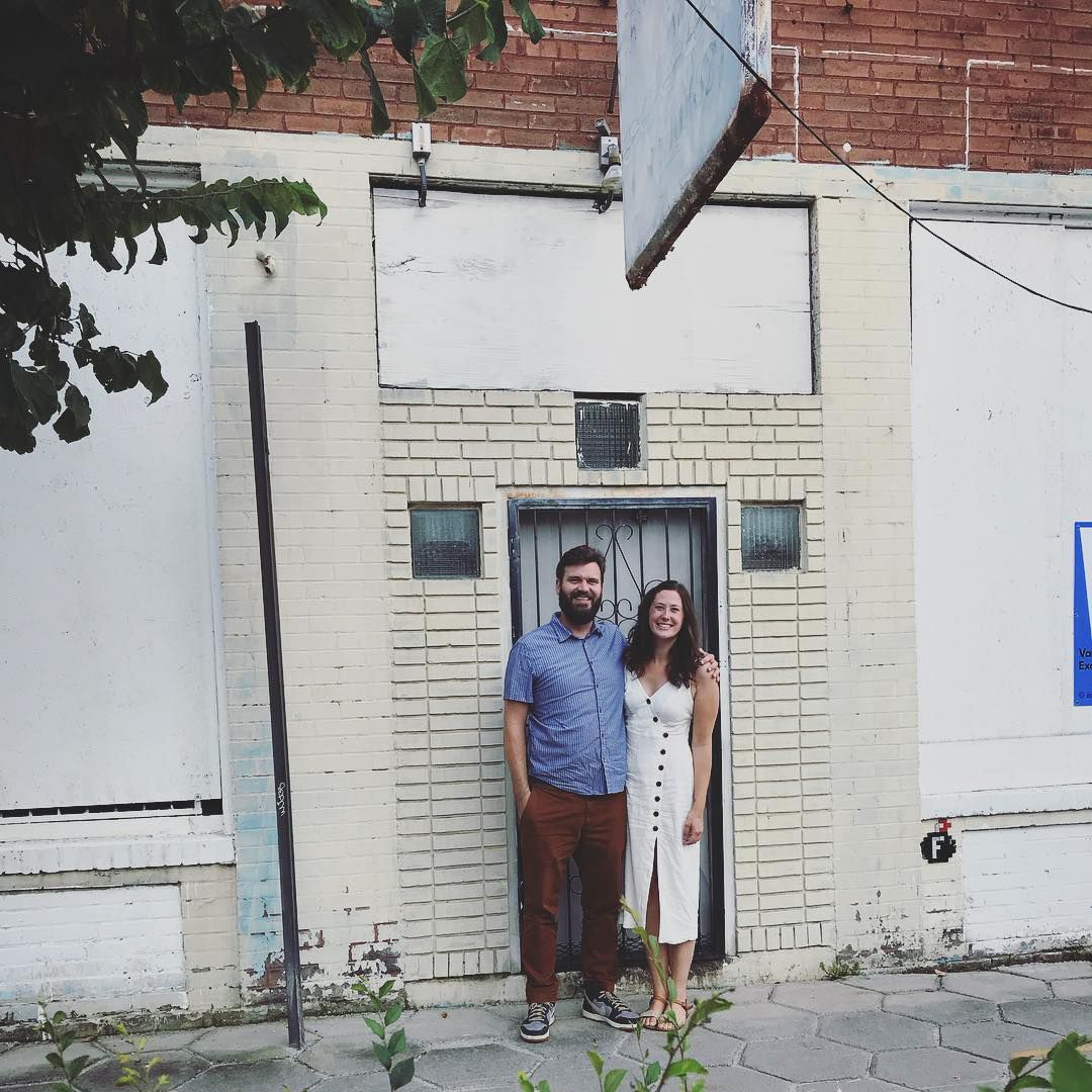 Emma and Sean Schacke standing in front of the white building before the renovation