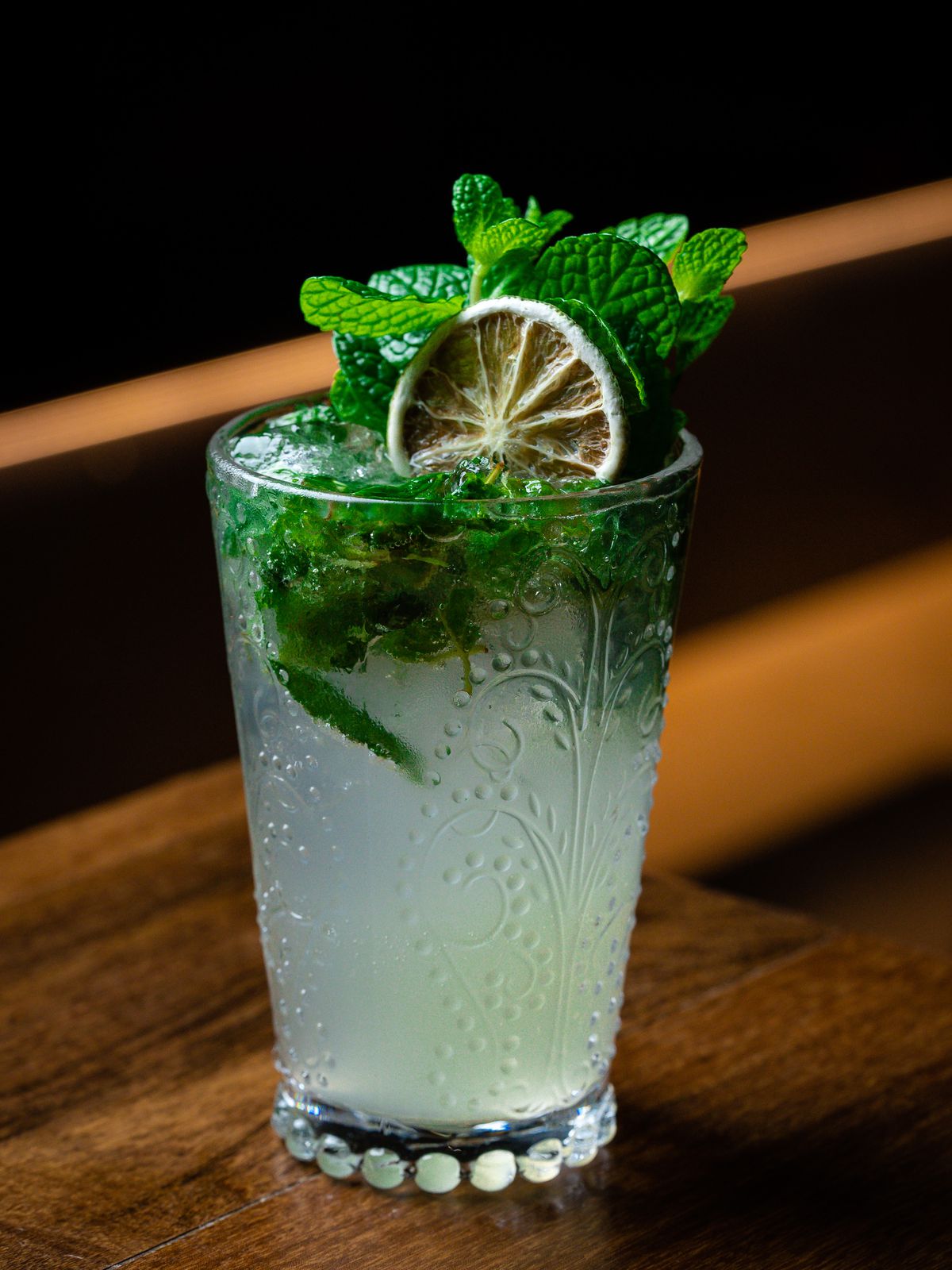 A cocktail garnished with mint leaves and lime.