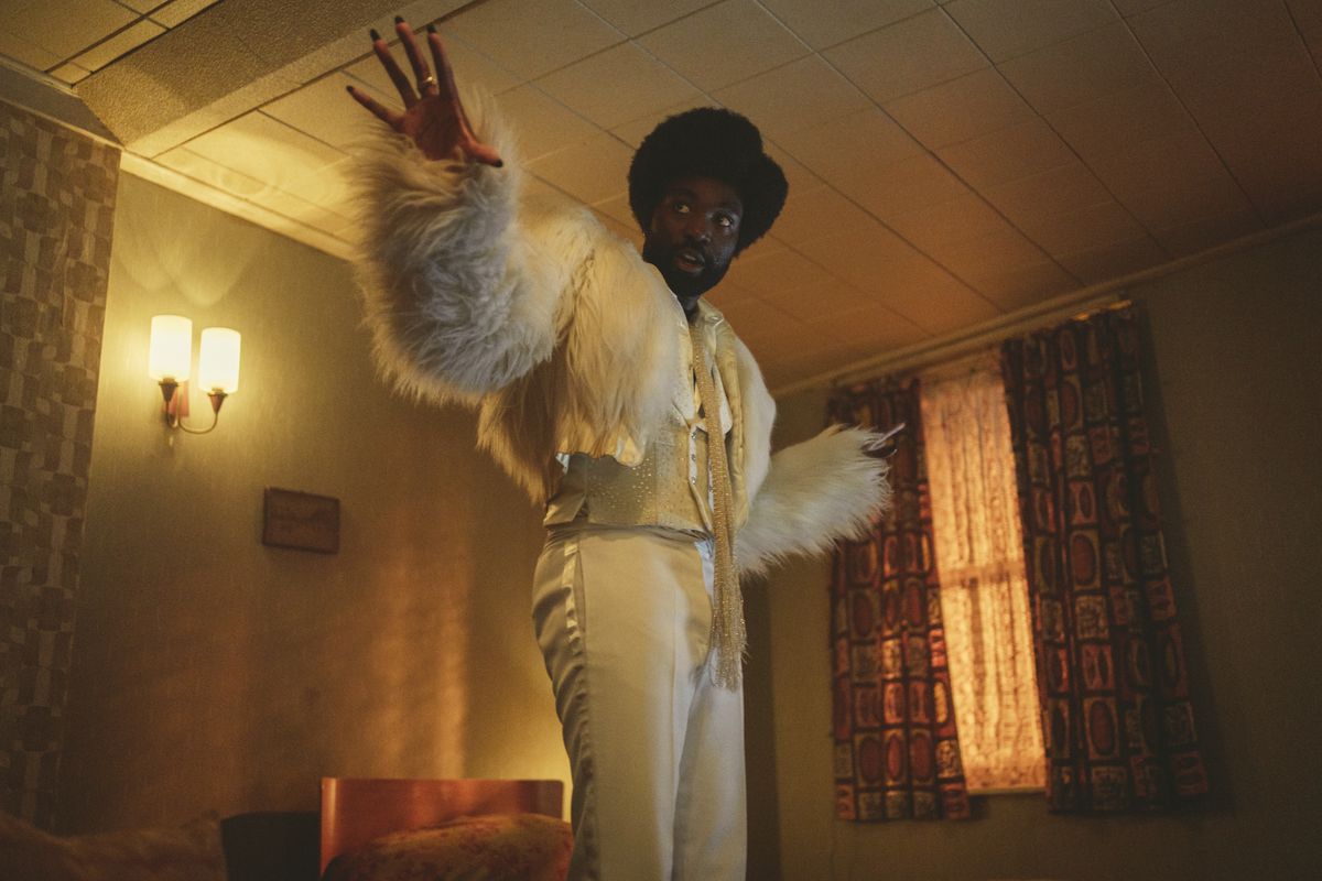 Paapa Essiedu in a flamboyant white outfit looking at something in a still from Black Mirror season 6