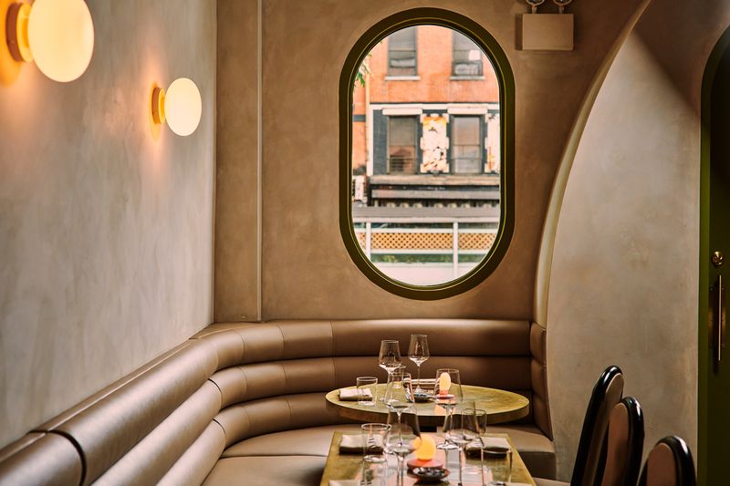 An oval window overlooks the street with several restaurant tables below.