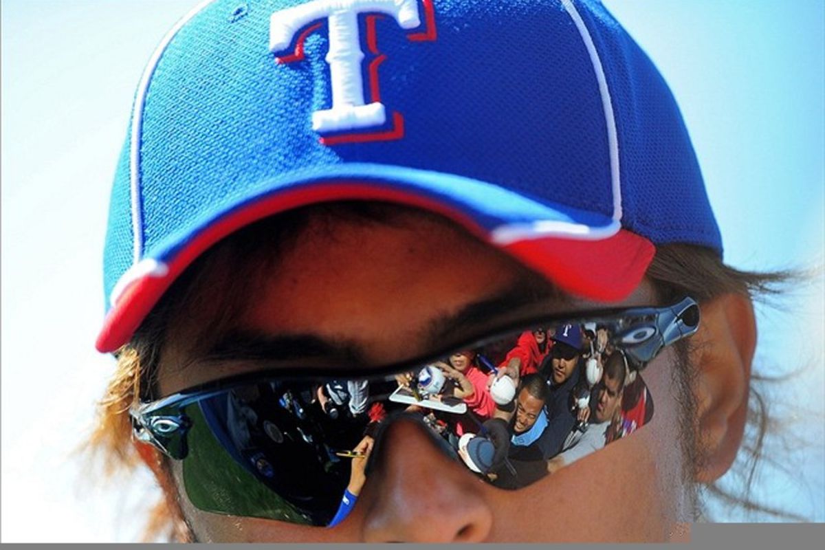 Mar. 1, 2012; Surprise, AZ, USA; Fans reflect in the sunglasses of Texas Rangers pitcher Yu Darvish as he signs autographs during spring training workouts at the practice fields at Surprise Stadium.  Mandatory Credit: Mark J. Rebilas-US PRESSWIRE