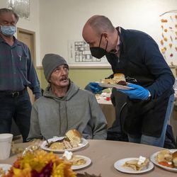 Timothy Sohn, center, chats with Utah Governor Spencer Cox as Cox serves Thanksgiving dinners at the Salt Lake City Rescue Mission in Salt Lake City on Monday, November 22, 2021.