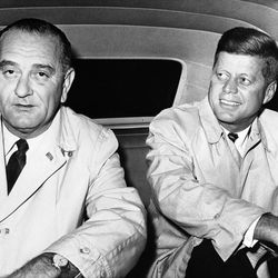 Senator John F. Kennedy, right, the Democratic presidential candidate, accompanied by running mate, Senator Lyndon Johnson, sits in a car outside hotel Biltmore in New York, Nov. 5, 1960. The pair was en route to the New York coliseum for a political rally aimed at gaining votes for the Democrats in Tuesday's election. Note candidates wear raincoats due to continuous inclement weather throughout the night. Republicans held a similar rally at the coliseum Wednesday.