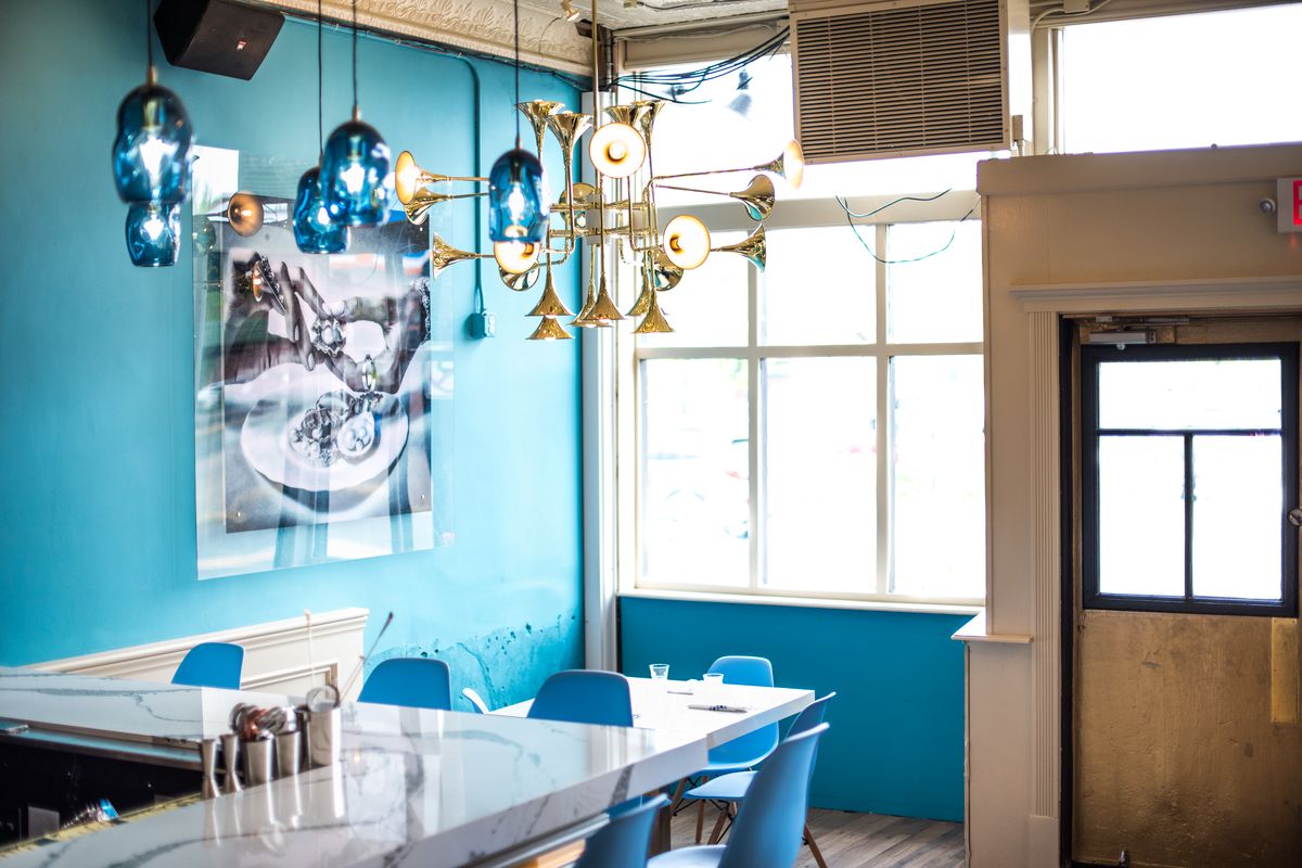 Vibrant light blue walls, white marble bar, and white table set inside the original Pearl &amp; the Thief location