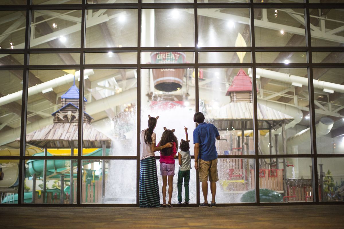 A family of four peering into Great&nbsp;Wolf&nbsp;Lodge’s indoor water park.