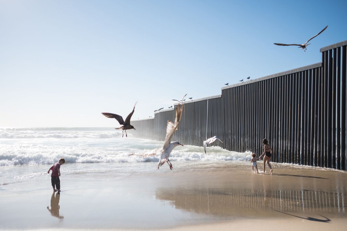 Kids play on a beach near the US-Mexico border wall.