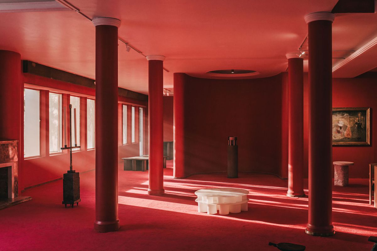 A living area where the floors and ceiling are painted red. There is a white table in the middle of the red room. 
